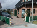 Hollzaun Standard 85cm unten gebogen. Grün gestrichen mit weißen Pfosten und Kugelkopfkappen, Klinkerhaus und Auto in Einfahrt
